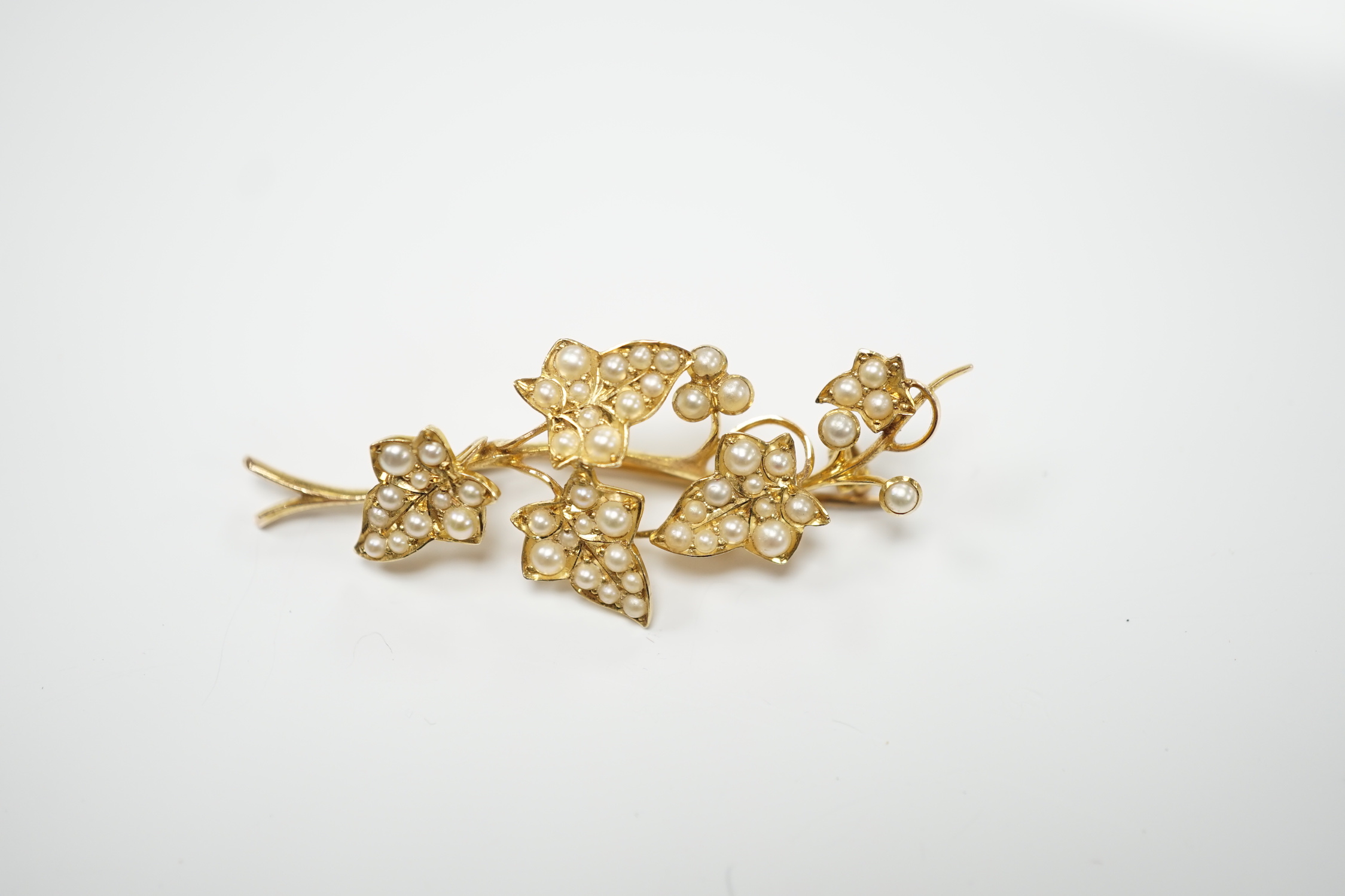 An Edwardian yellow metal and seed pearl set spray brooch, 45mm, together with a similar yellow metal and turquoise cluster set pendant with glazed back.